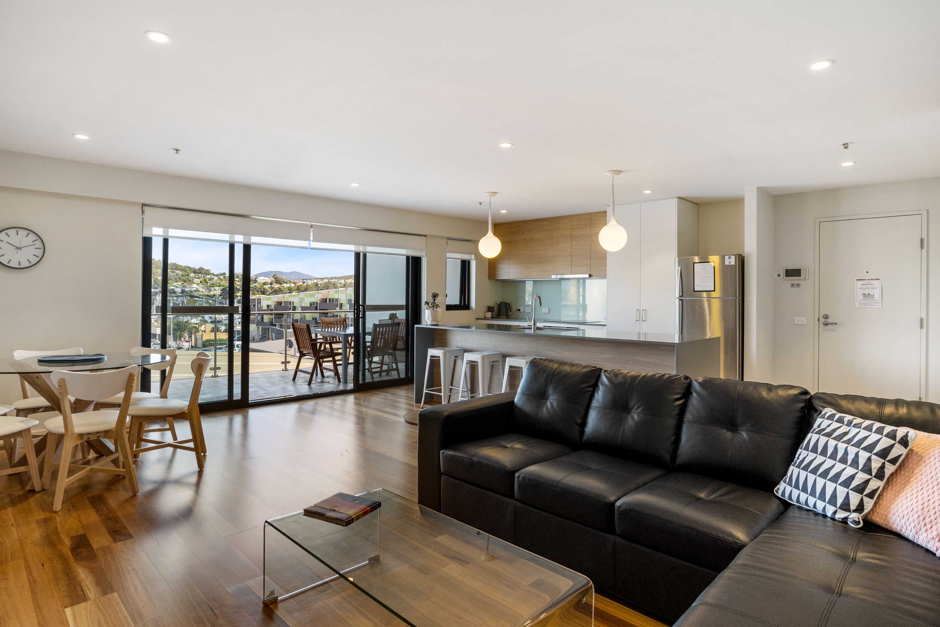 A modern living room with a leather sofa, a glass coffee table, and a dining area with a table and chairs.