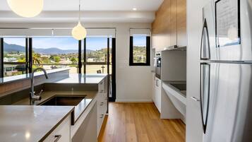 Una cocina moderna con una isla grande, electrodomésticos de acero inoxidable y amplias ventanas con vistas a la ciudad y las montañas.