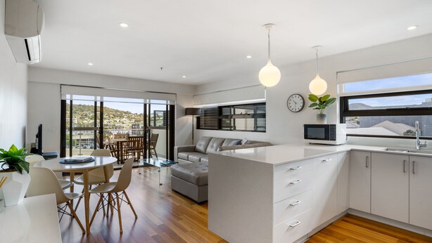 Una cocina moderna con una isla central, un área de comedor con mesa y sillas, y vista al exterior.