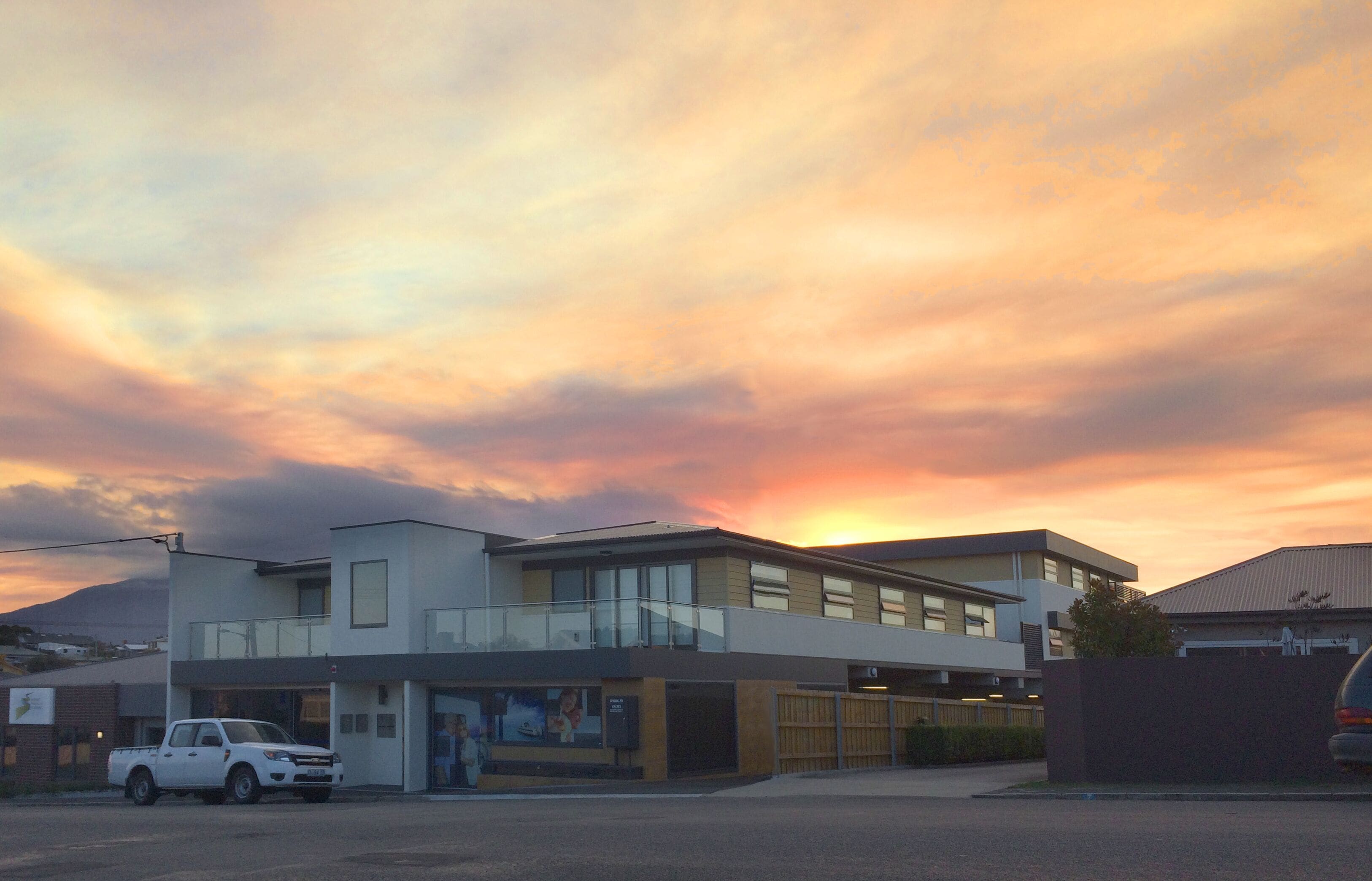 A modern building with a flat roof and a balcony on the second floor.