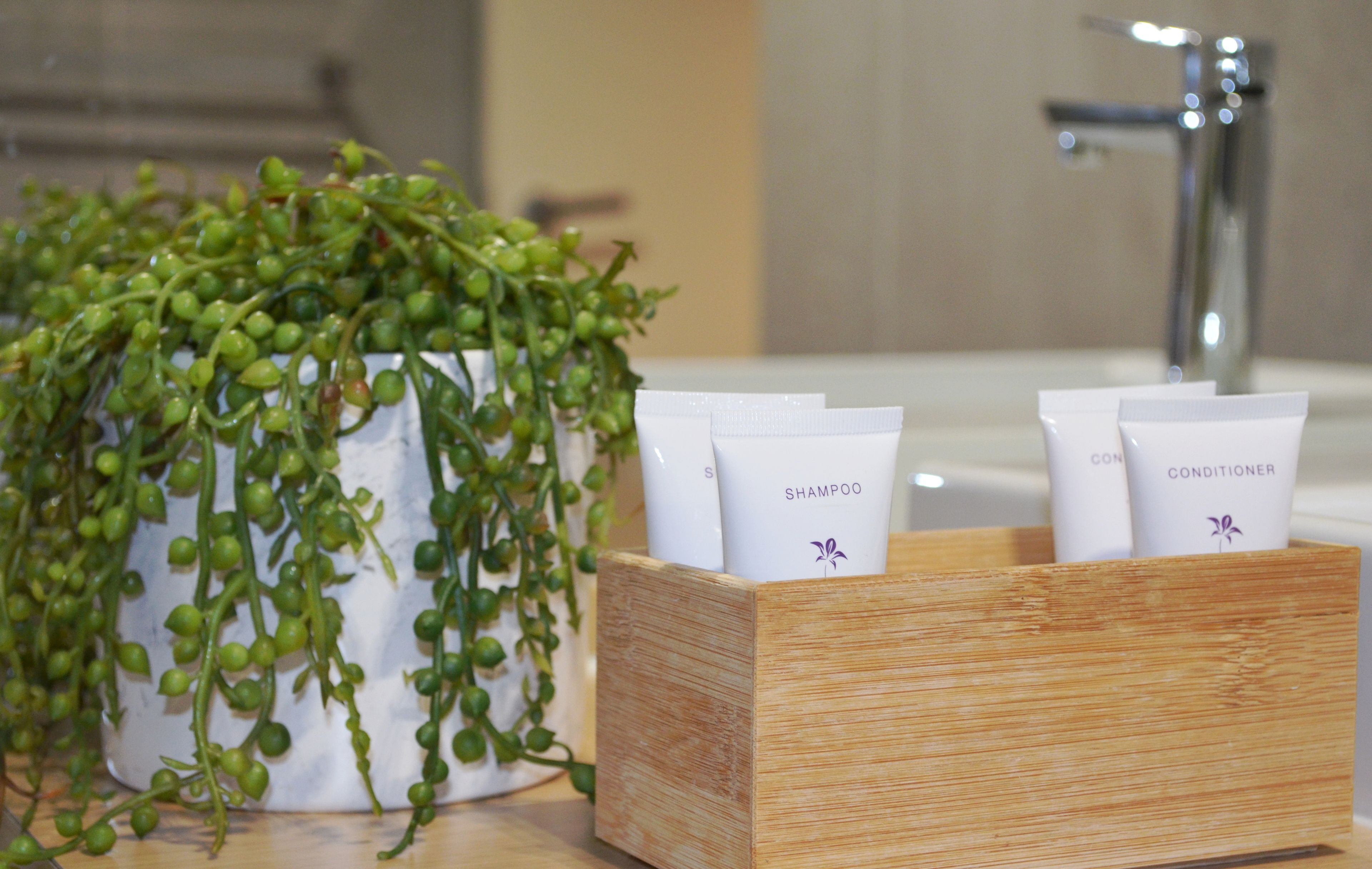 A bathroom with a wooden box containing two white tubes labeled "SHAMPOO" and "CONDITIONER".