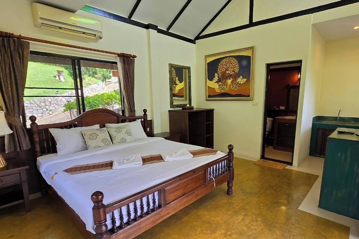 Un dormitorio con cama de madera, mesita de noche, cómoda y ventana con cortinas.