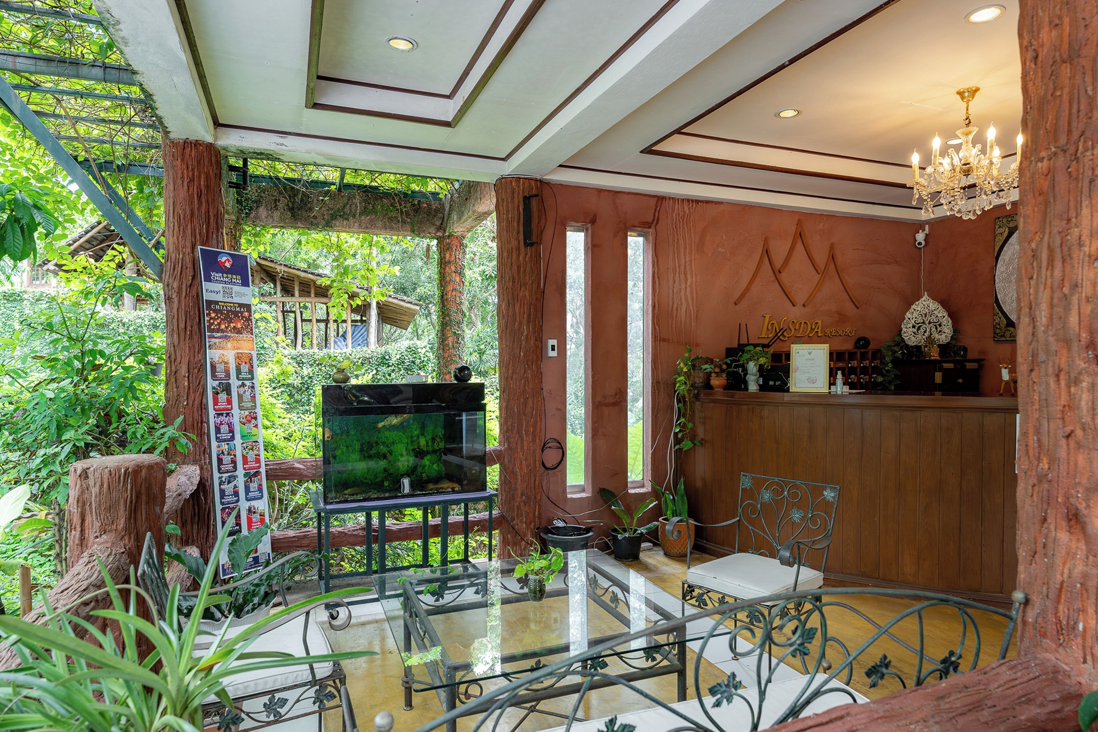 Habitación amplia con un acuario grande, muebles de madera y vistas al exterior con vegetación.