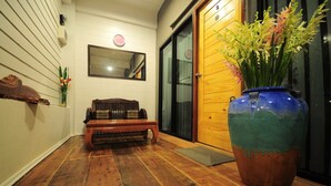 Un banco de madera, un jarrón grande con flores y una puerta de madera.