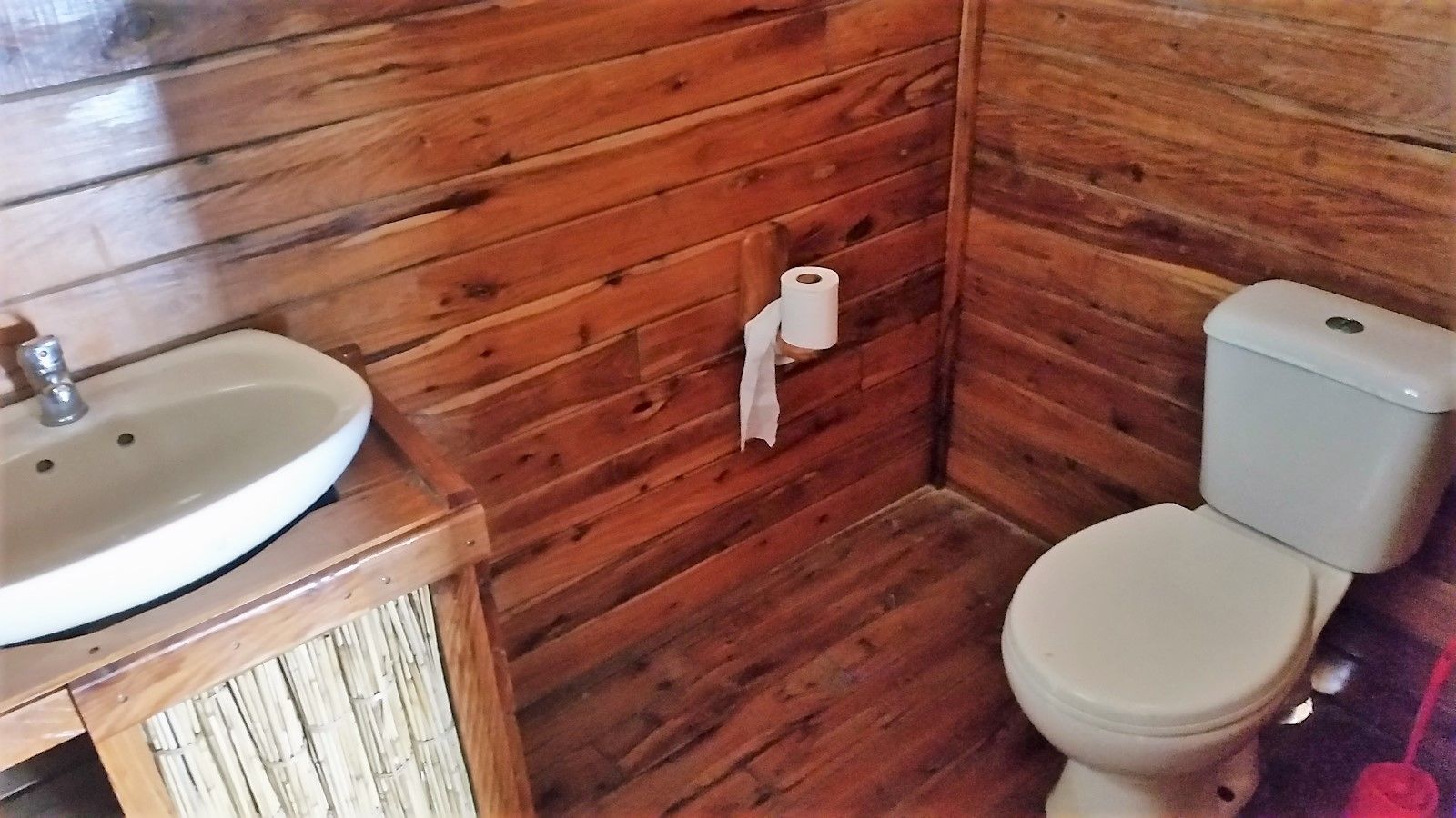 A wooden bathroom with a sink and toilet.