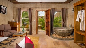 A spacious room with a large bathtub, a sofa, a coffee table, and a view of a lush garden. - Model Residence and Spa (Siem Reap)