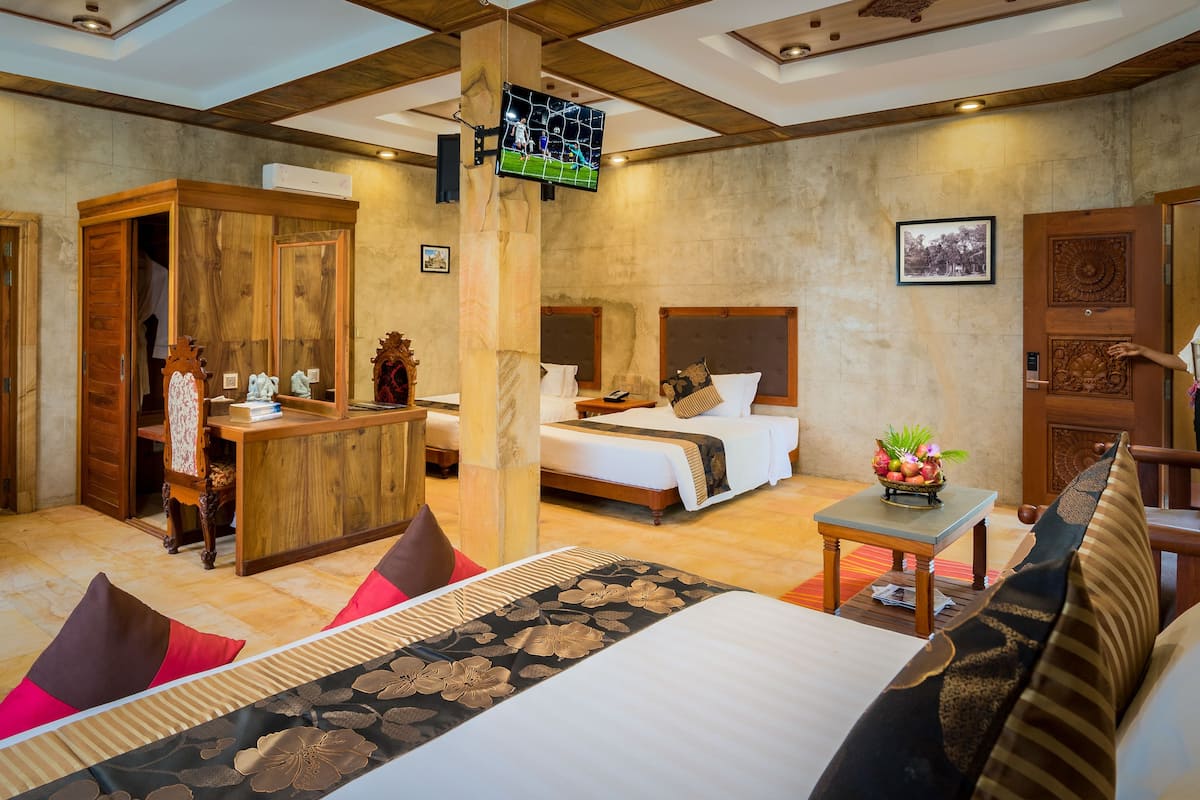 A hotel room with a bed, a wooden desk, a television, and a bathroom with a bathtub.