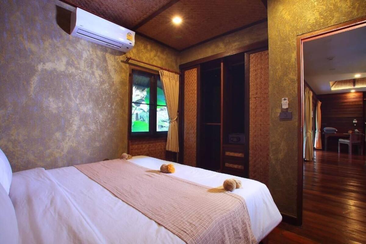A hotel room with a bed, a window with curtains, a door, and a view of a building outside.