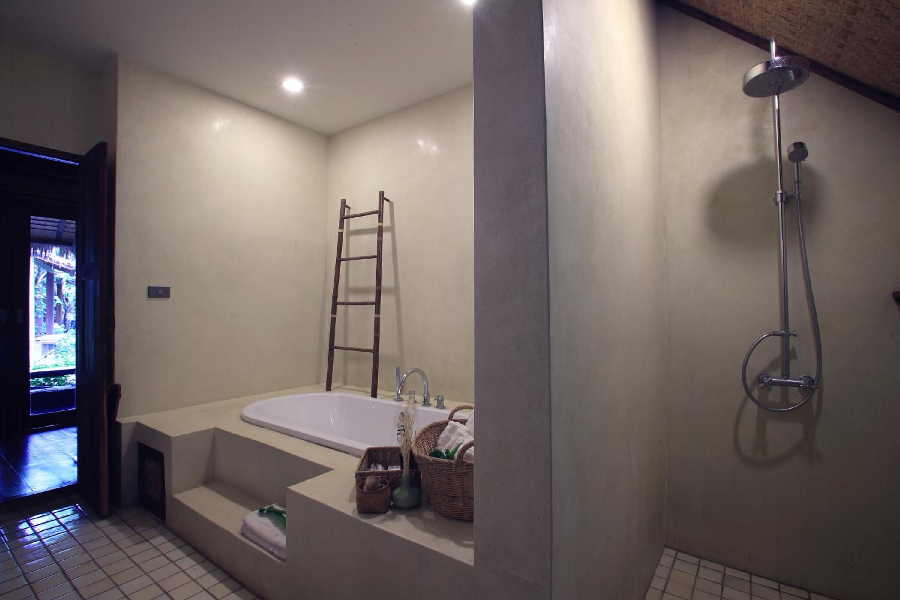A modern bathroom with a large bathtub, a shower, and a ladder against the wall.