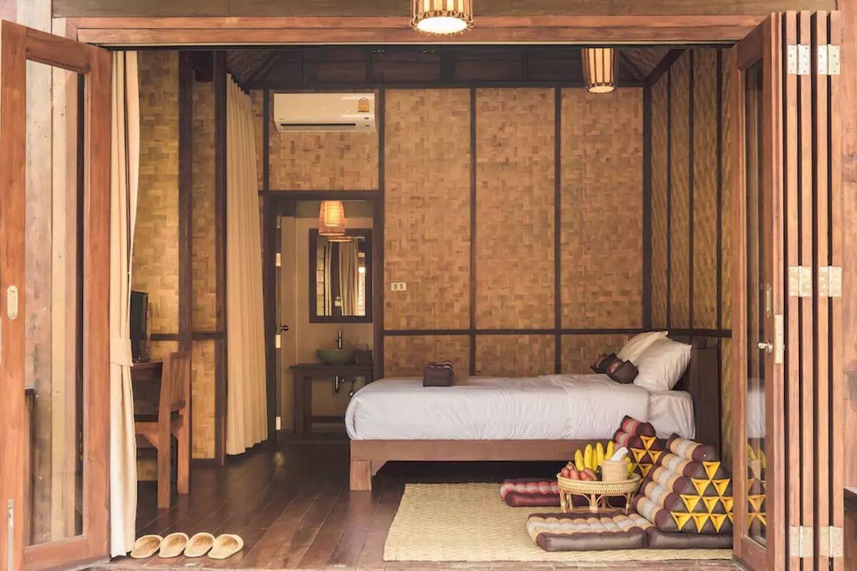 A wooden room with a bed, a small table, and a mirror.