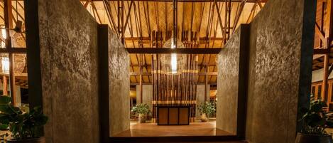 A spacious interior with a high ceiling, wooden beams, and a central hanging light fixture.