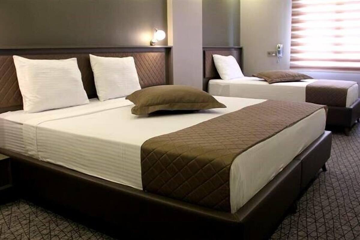 A hotel room with a large bed, a smaller bed, and a nightstand.