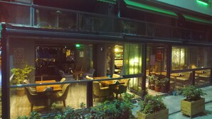Un restaurante con terraza, zona de bar y plantas en macetas.