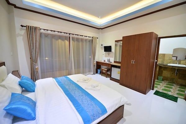A hotel room with a bed, a desk, a wardrobe, and a bathroom.