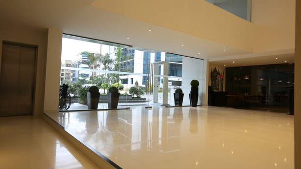 A spacious lobby with a large glass entrance, potted plants, and a view of the outside buildings. - Deccan Serai (Hyderabad)