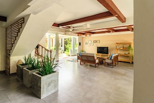 A spacious living area with a staircase, seating, and a television.