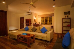 Uma sala de estar com sofá, mesa de centro e estante de livros.