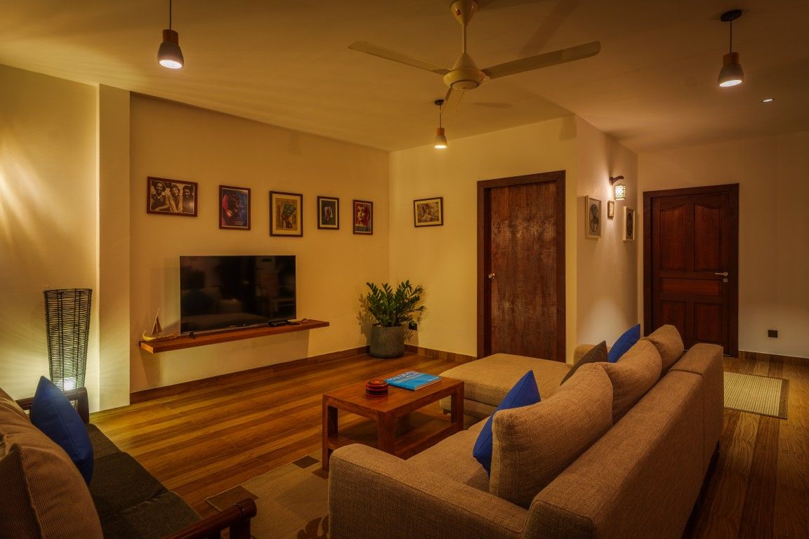 A living room with a sofa set, a coffee table, a television, and a ceiling fan.