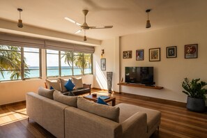 Una sala de estar con sofá, televisión y una obra de arte en la pared.