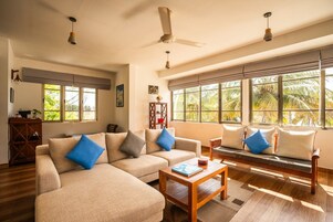 A living room with a sofa, a bench, a coffee table, and a ceiling fan.