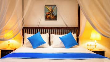 A bed with white and blue bedding, two blue pillows, a wooden headboard, a painting on the wall, and two bedside lamps.