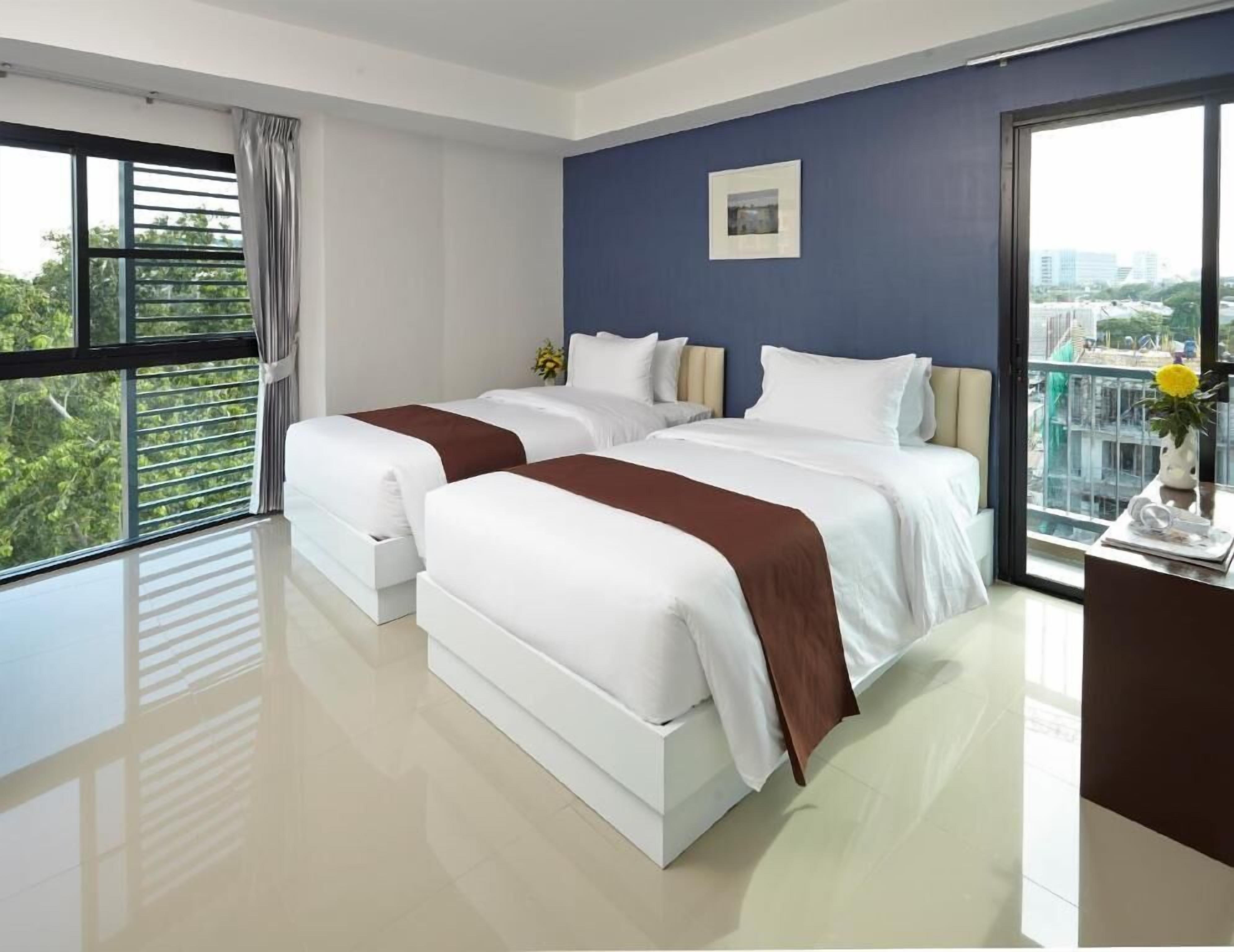 Une chambre d’hôtel avec deux lits, une grande fenêtre et une vue sur la ville.
