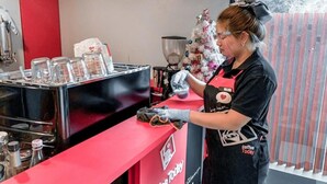 A coffee shop counter with a red and black color scheme, a coffee machine, and a Christmas tree in the background. - Casa Residence Hotel (Bangkok)