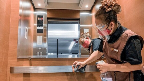 A person cleaning a wooden floor in an elevator. - Casa Residence Hotel (Bangkok)