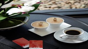 A tray with two white cups of coffee, a small potted plant with white flowers, and two red cards with the word "CASA" on them. - Casa Residence Hotel (Bangkok)