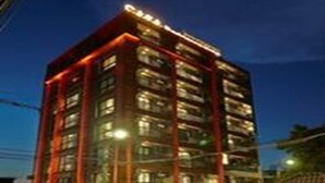 A multi-story hotel with a red exterior and illuminated windows. - Casa Residence Hotel (Bangkok)