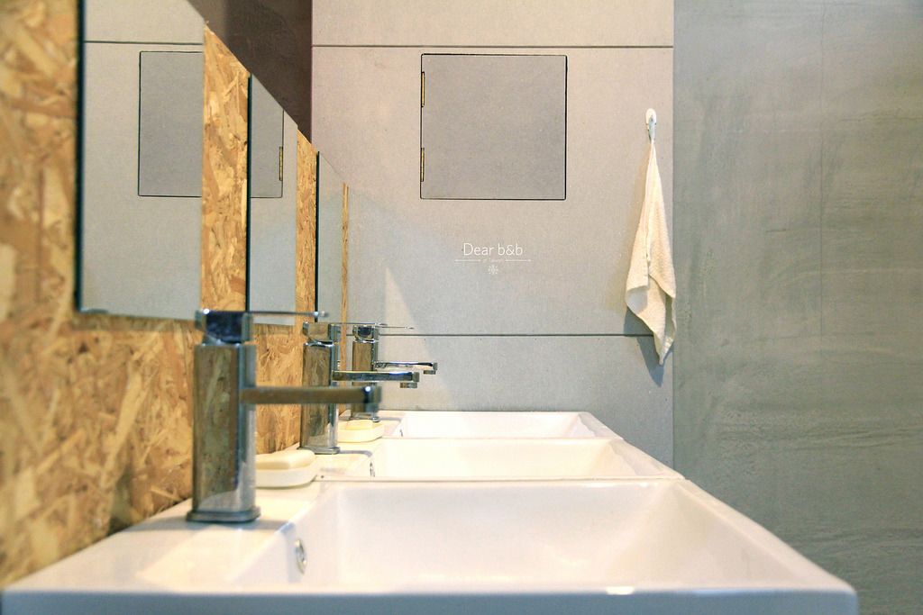 Uma casa de banho moderna com duas bacias, um espelho e uma toalha pendurada na parede.