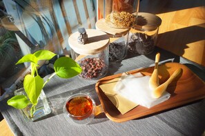 A table with jars of spices, a small plant, a tray with a wooden spoon, and a glass of tea. - Puli Center Center Hostel (Puli)