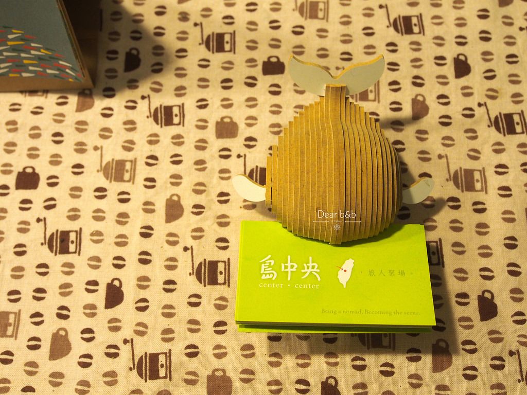 Un adorno con una figura de pájaro sobre una tarjeta verde con texto japonés.