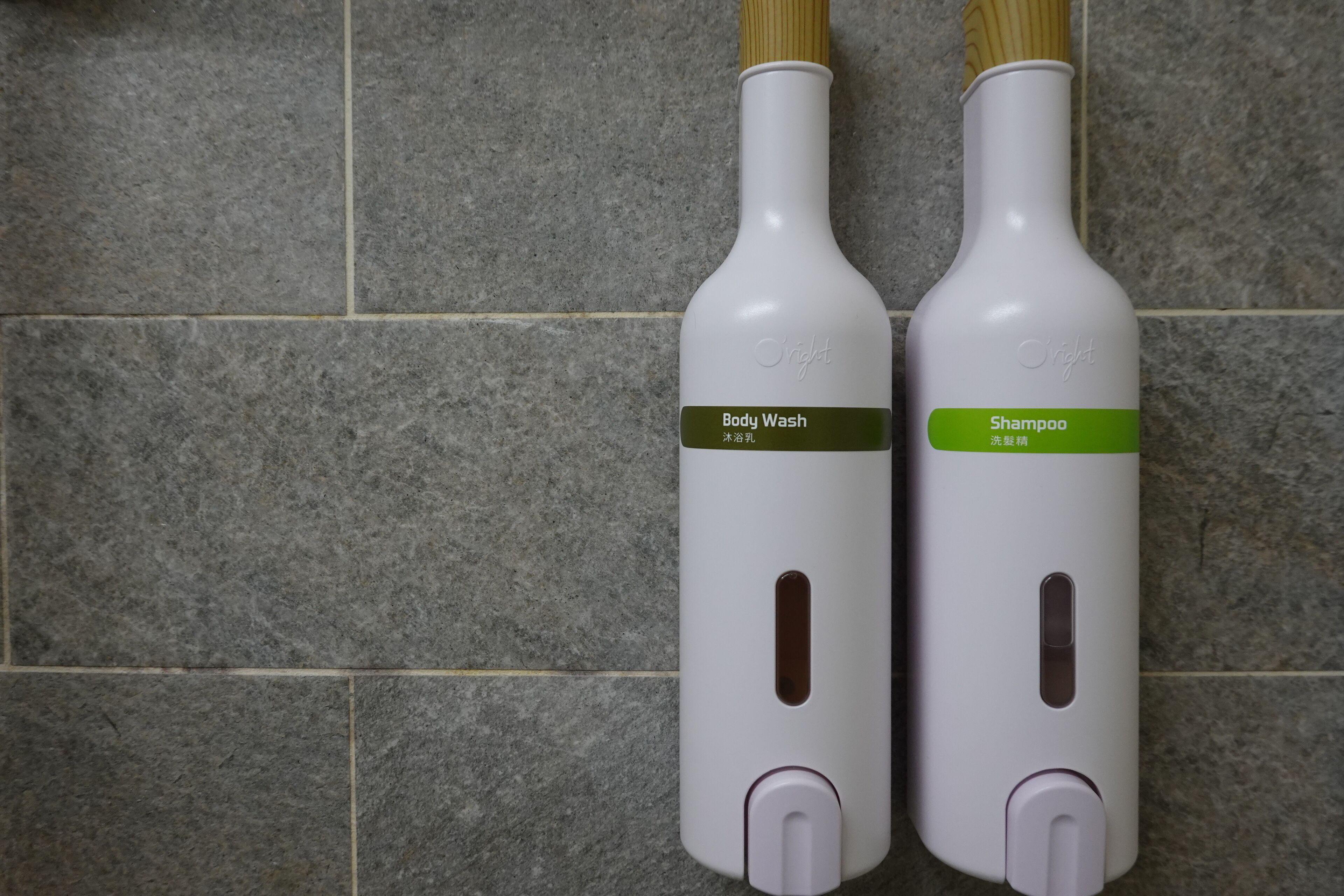 Dos botellas de jabón corporal y champú sobre una pared de azulejos.