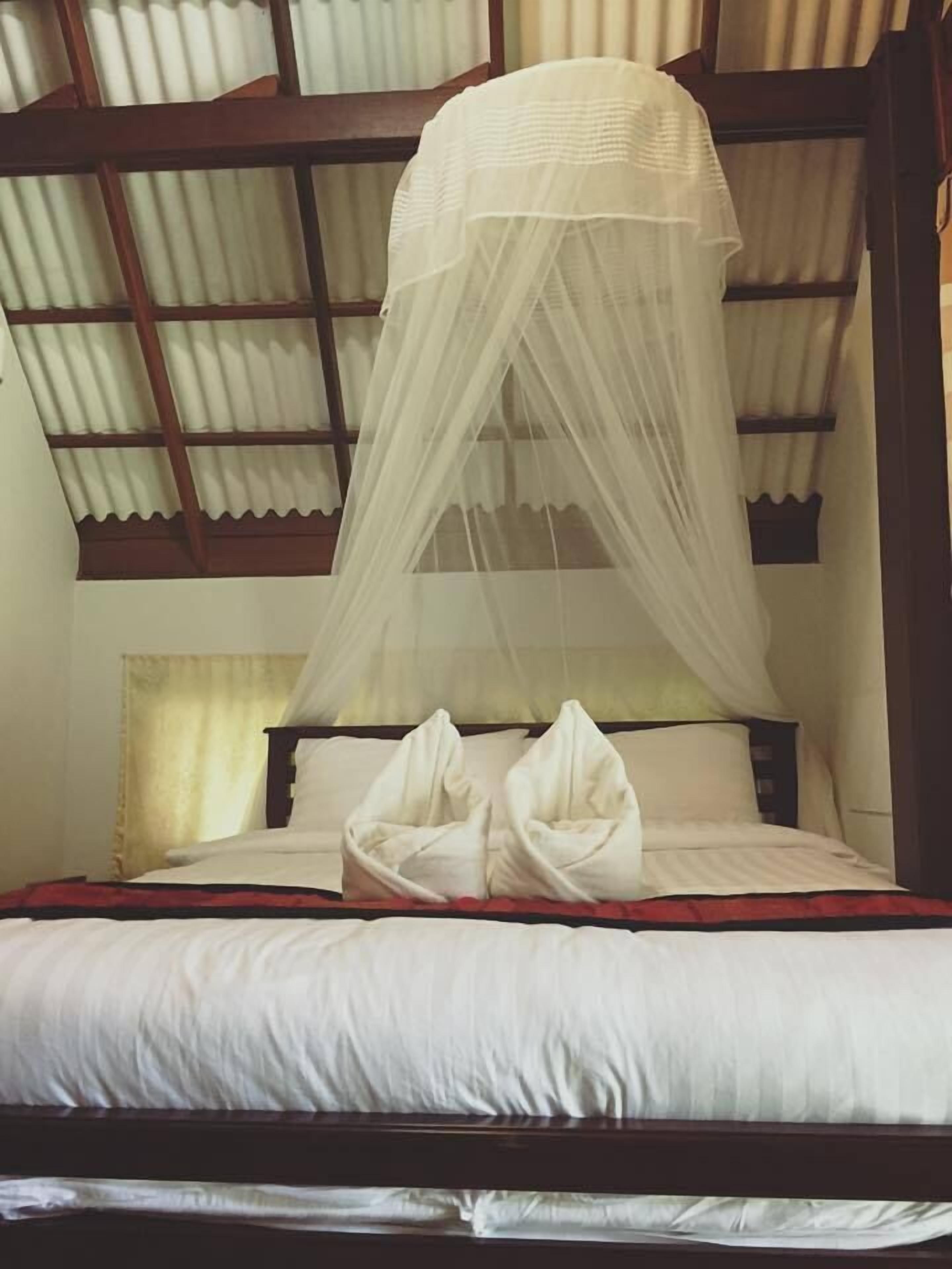 Una cama con dosel, cabecera de madera y colcha roja y blanca.