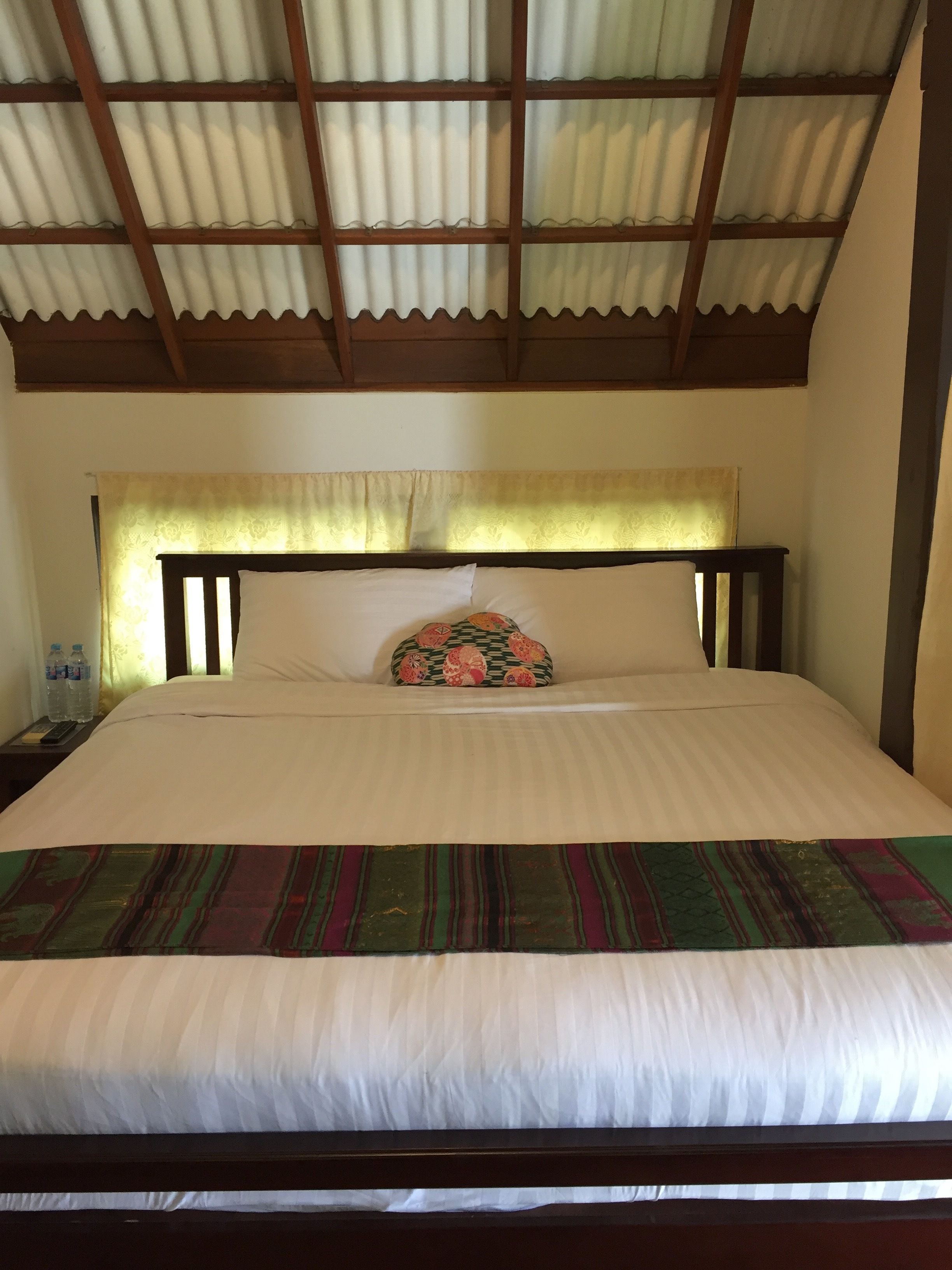 A bed with a striped bedspread, a decorative pillow, and a wooden headboard.