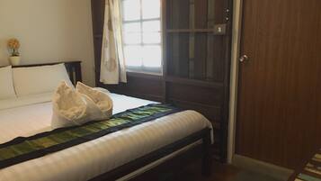 Un dormitorio con cama, una ventana con cortinas, una puerta de madera y una pequeña planta en maceta.