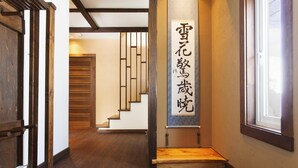 A hallway with wooden flooring, a staircase, and a wall with a vertical sign. - Ginsetsu (Kutchan)