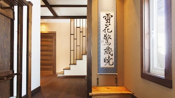 Un pasillo con suelo de madera, una escalera y una pared con un letrero vertical.