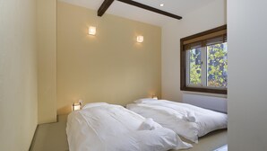 A hotel room with two beds, a window with a view of greenery, and two wall-mounted lights. - Ginsetsu (Kutchan)