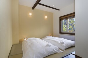 Habitación de hotel con dos camas, una ventana que da a zonas verdes y dos lámparas de pared.