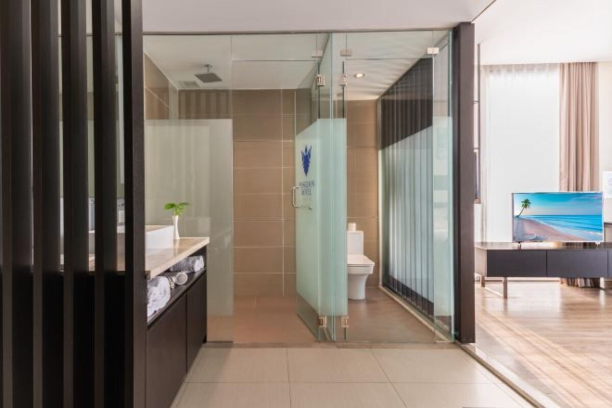 Un bagno moderno con cabina doccia in vetro, un water e un lavandino con porta asciugamani.