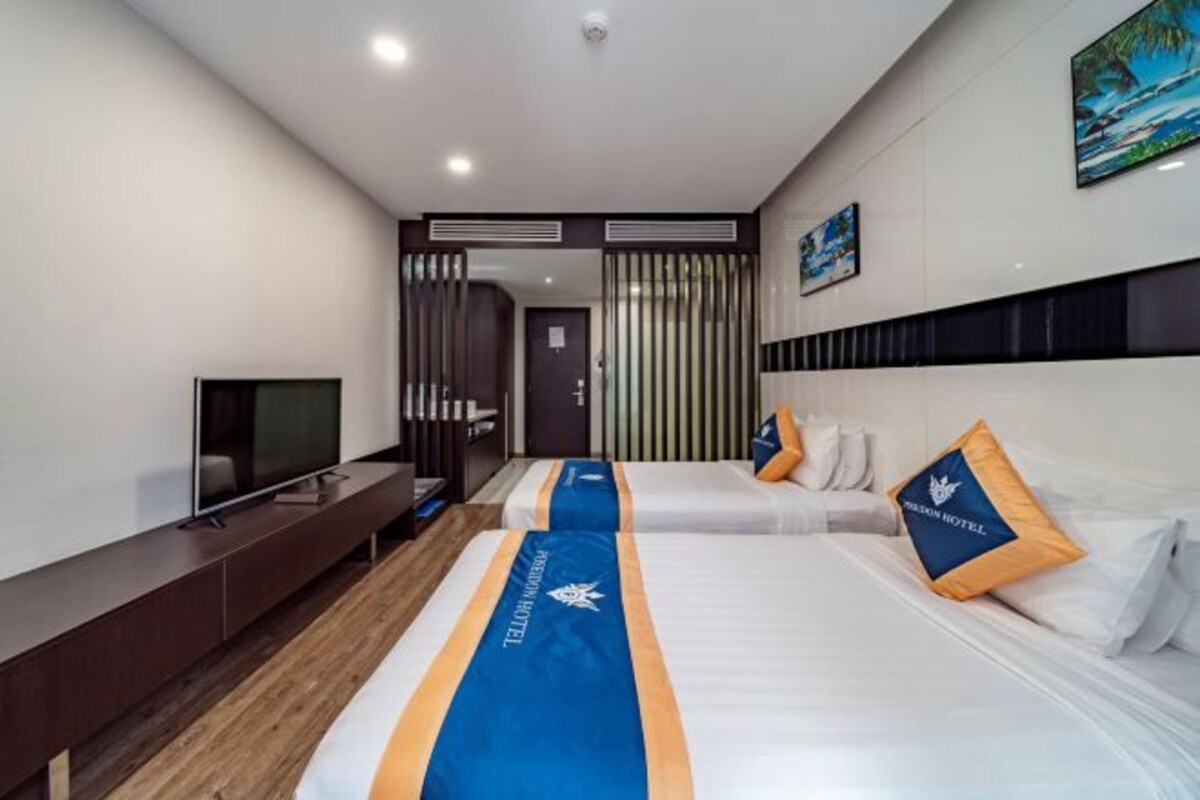 Camera d'albergo con due letti, televisore e minibar.