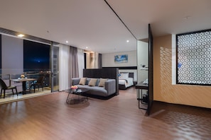 A modern hotel room with a balcony, a sofa, a dining table, and a bed. - Poseidon Nha Trang Hotel (Nha Trang)