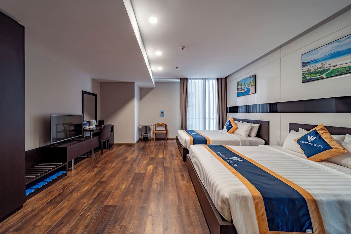 Een hotelkamer met twee bedden, een bureau, een televisie en uitzicht op de omgeving.
