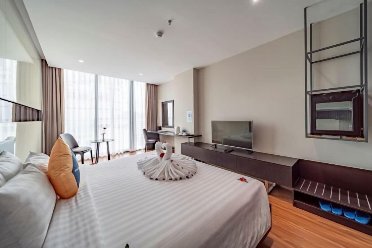 Een moderne hotelkamer met een groot bed, een bureau, een televisie en een kledingkast.