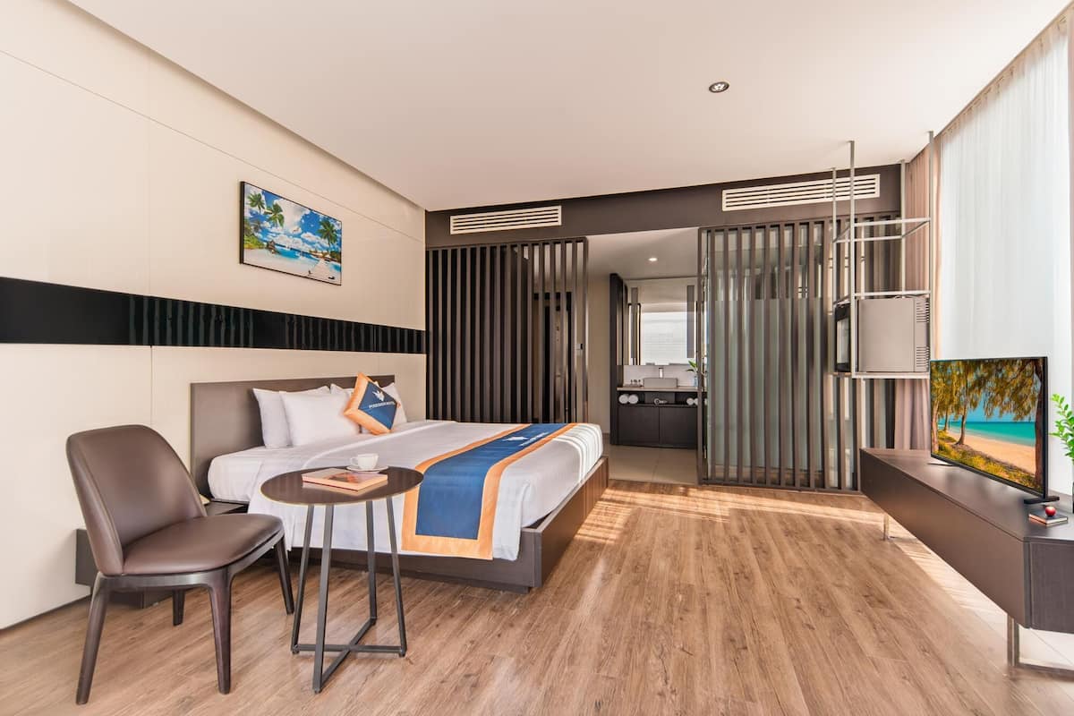 Een moderne hotelkamer met een bed, bureau, stoel en televisie.