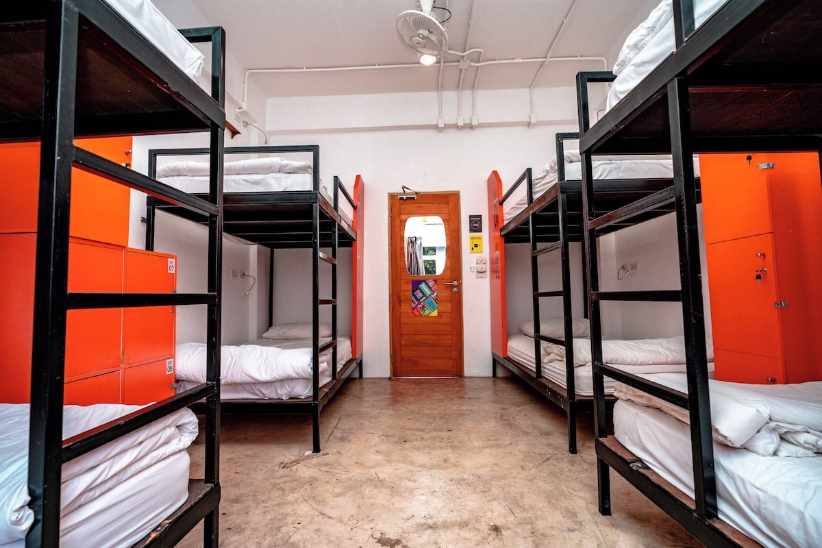 Un dormitorio con literas, taquillas anaranjadas y una puerta de madera.