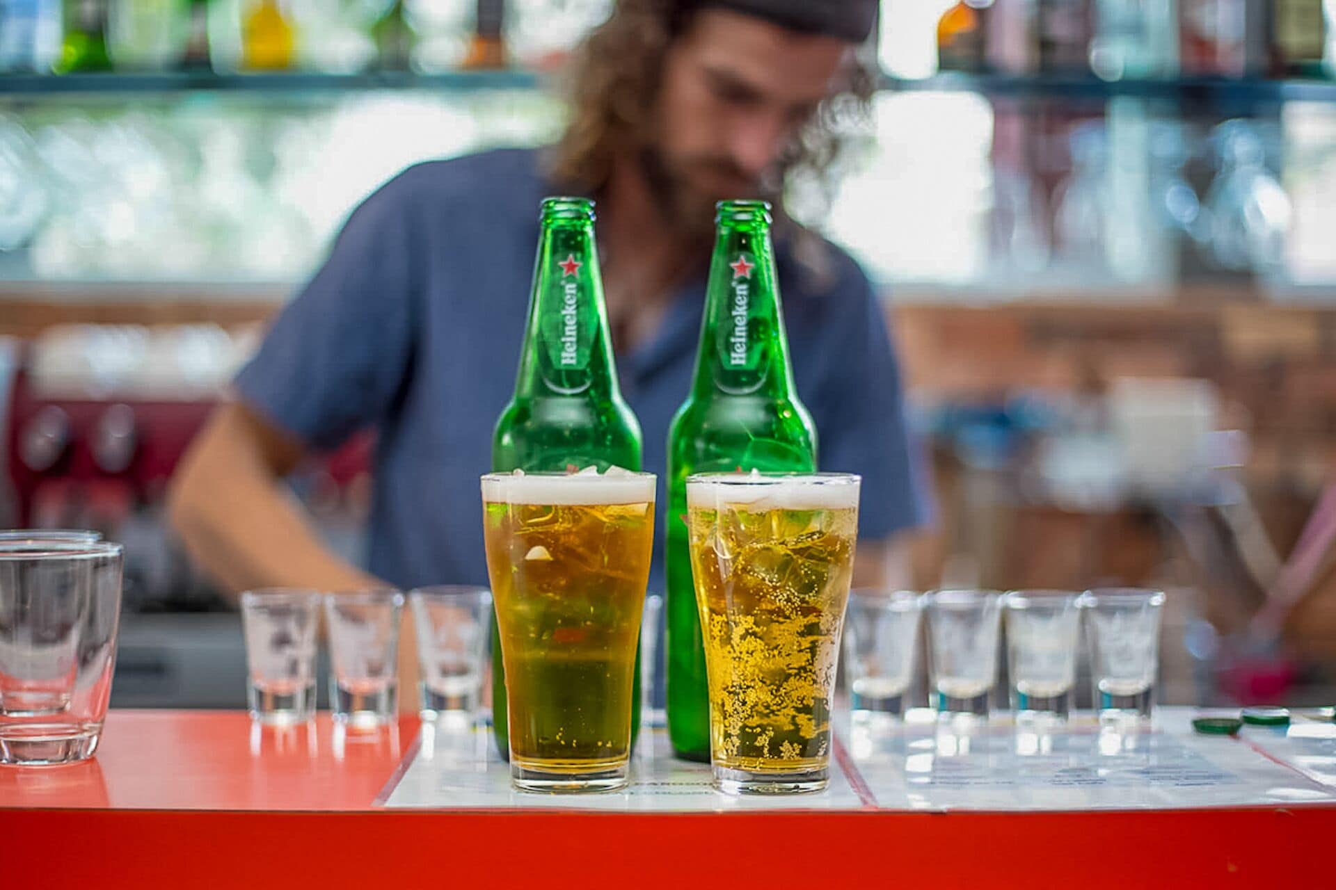 Dos botellas de cerveza y dos vasos sobre una barra.