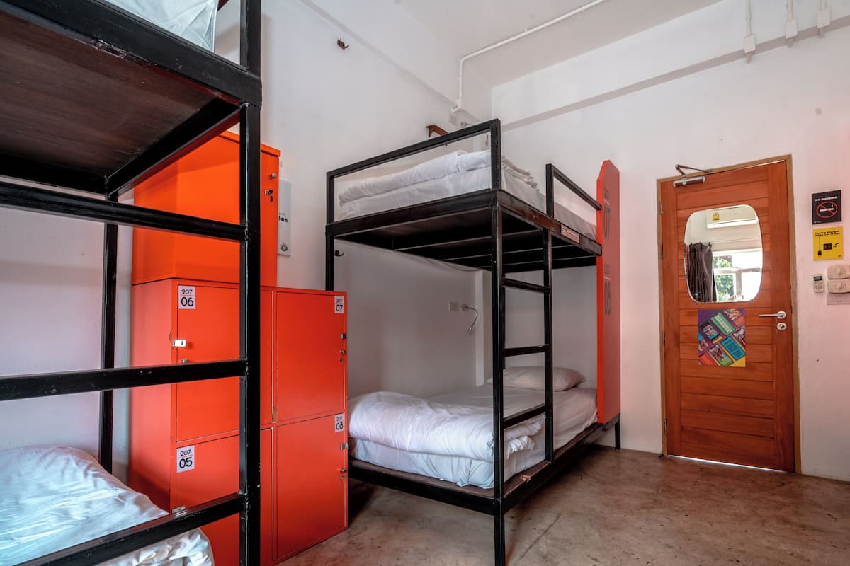 Un dormitorio con literas, una puerta de madera y casilleros naranjas.